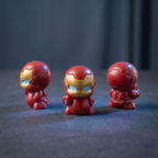 Three small Iron Man chibi figurines in red and gold armor are arranged on a dark surface against a dark gray background, with the center figure facing forward and the side figures turned sideways.

Three front and back views of a mini iron superhero figurine